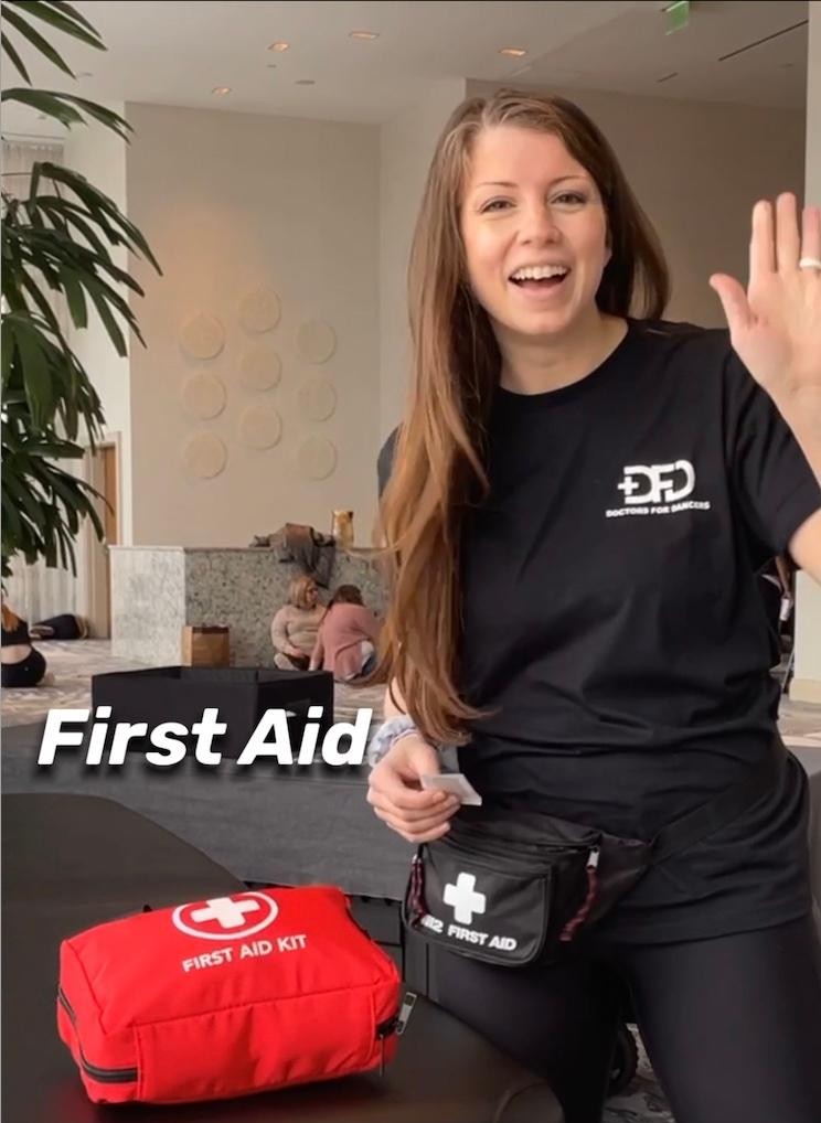 DFD Dance Specialist Dr. Jenna Loewer waving hello beside a first aid kit at Velocity Dance Convention in Norfolk, Virginia